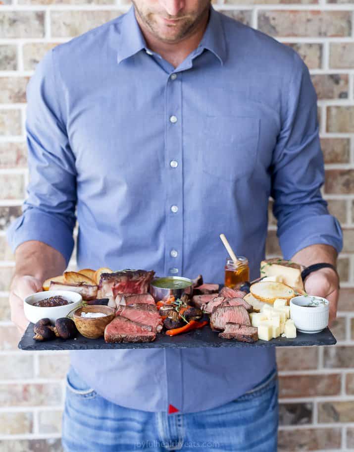 man holding a steak charcuterie board