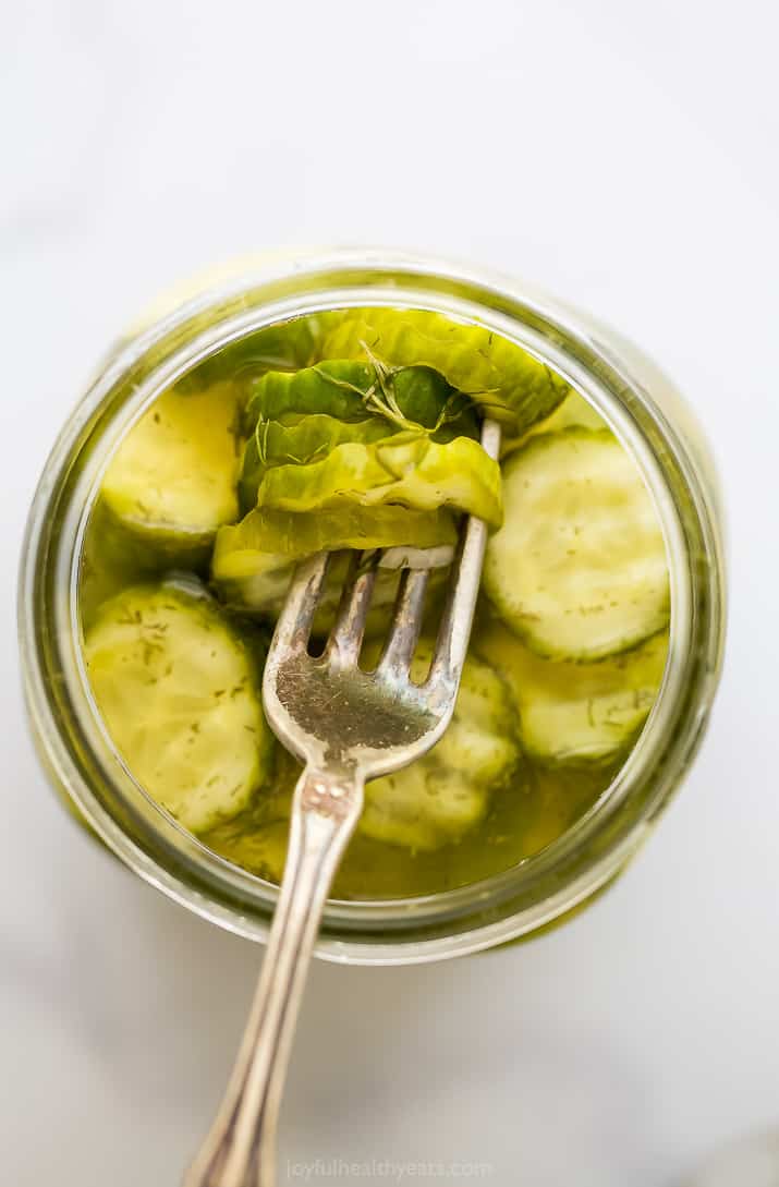fork with pickles in a jar filled with dill pickles