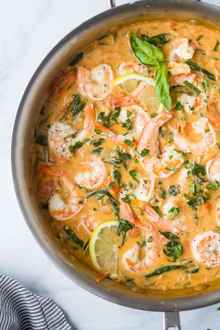 a skillet filled with shrimp in a cream sauce and tomatoes