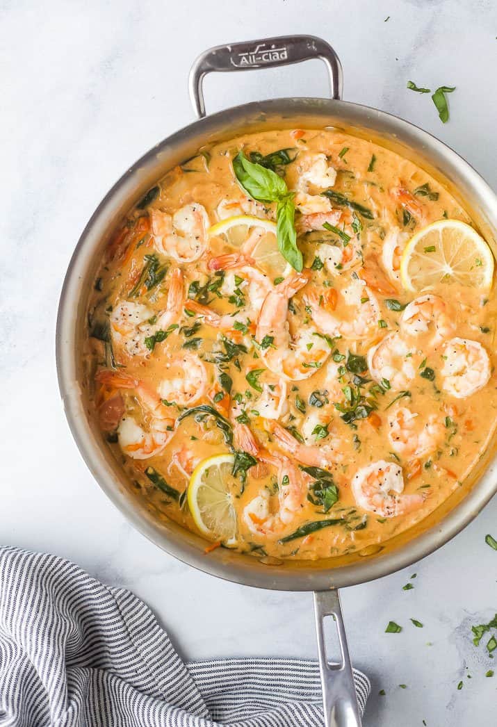 a skillet filled with shrimp in a cream sauce and tomatoes