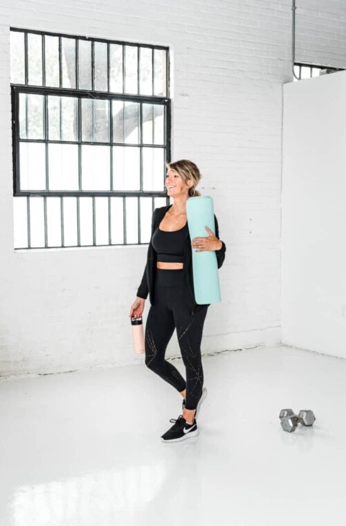 girl in workout gear holding a yoga mat