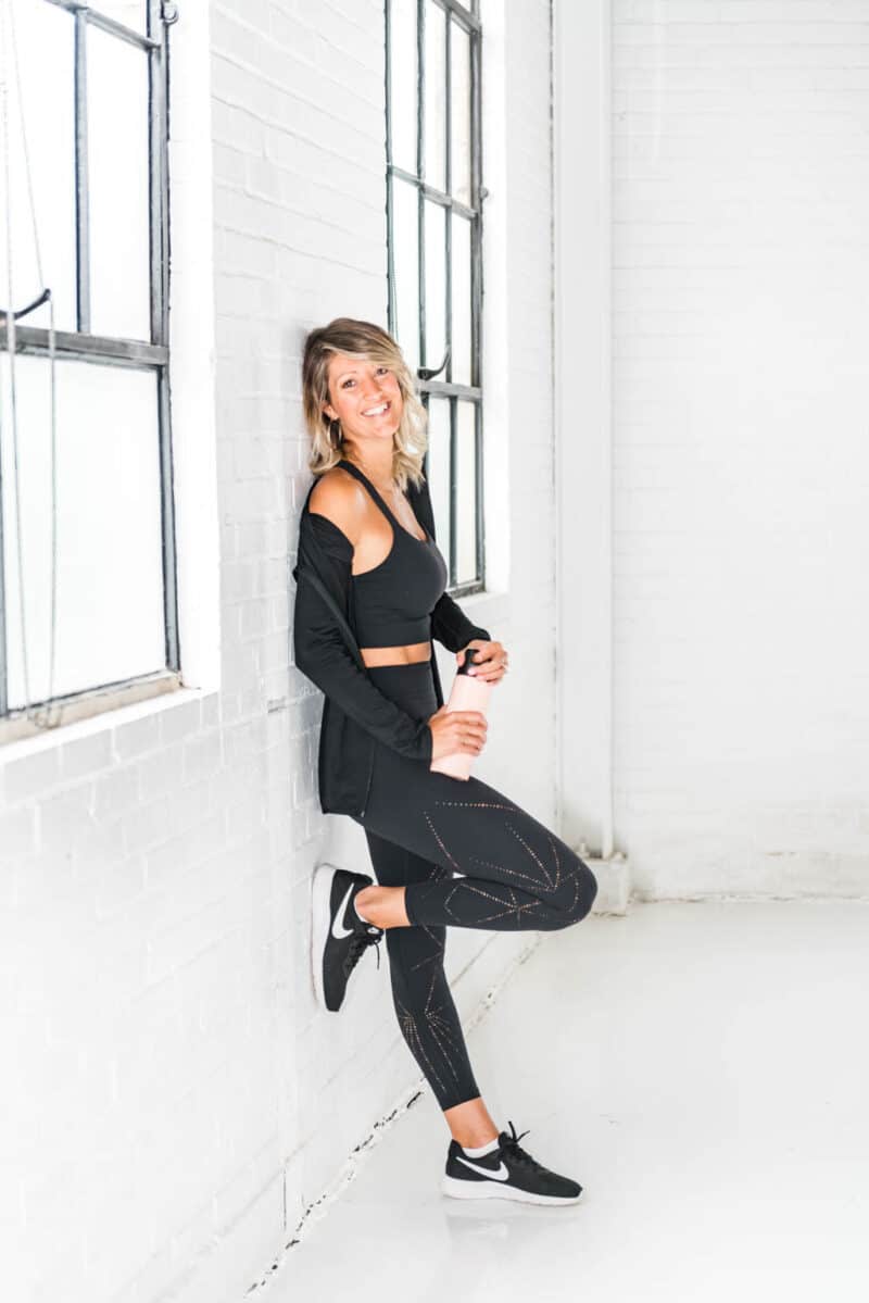 a girl in black workout gear leaning up against a wall