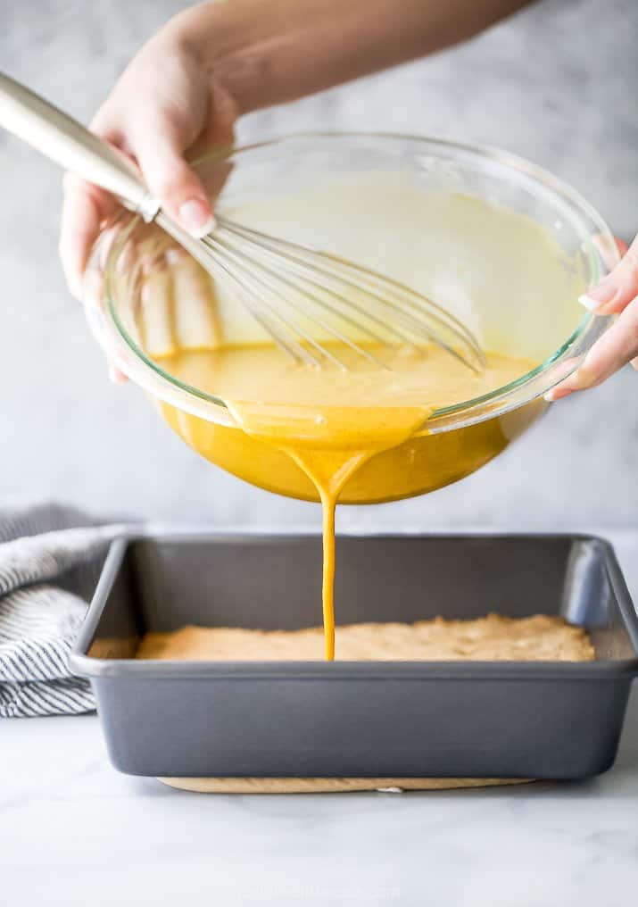 pouring pumpkin pie filling into an almond crust