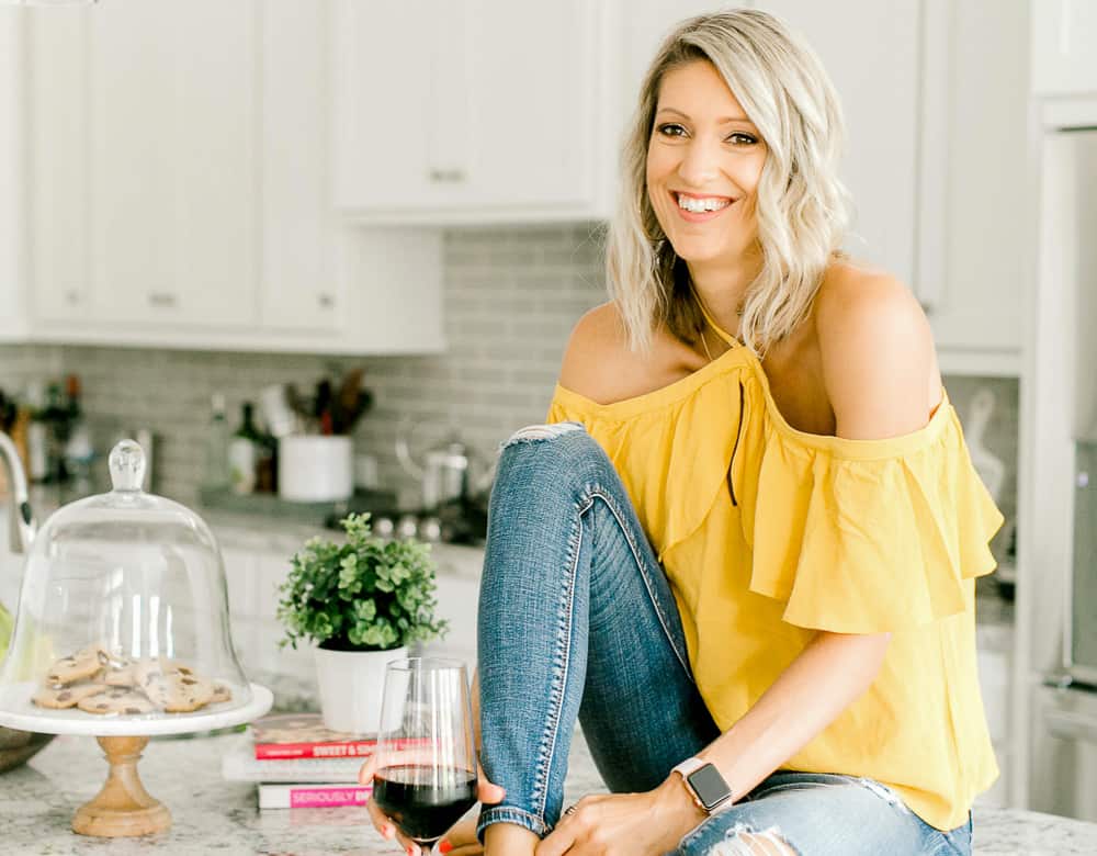 Krista sitting on a counter with a glass of wine