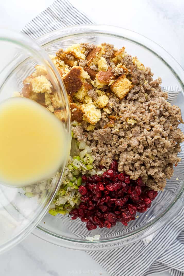 pouring vegetable broth into a bowl of stuffing mixture