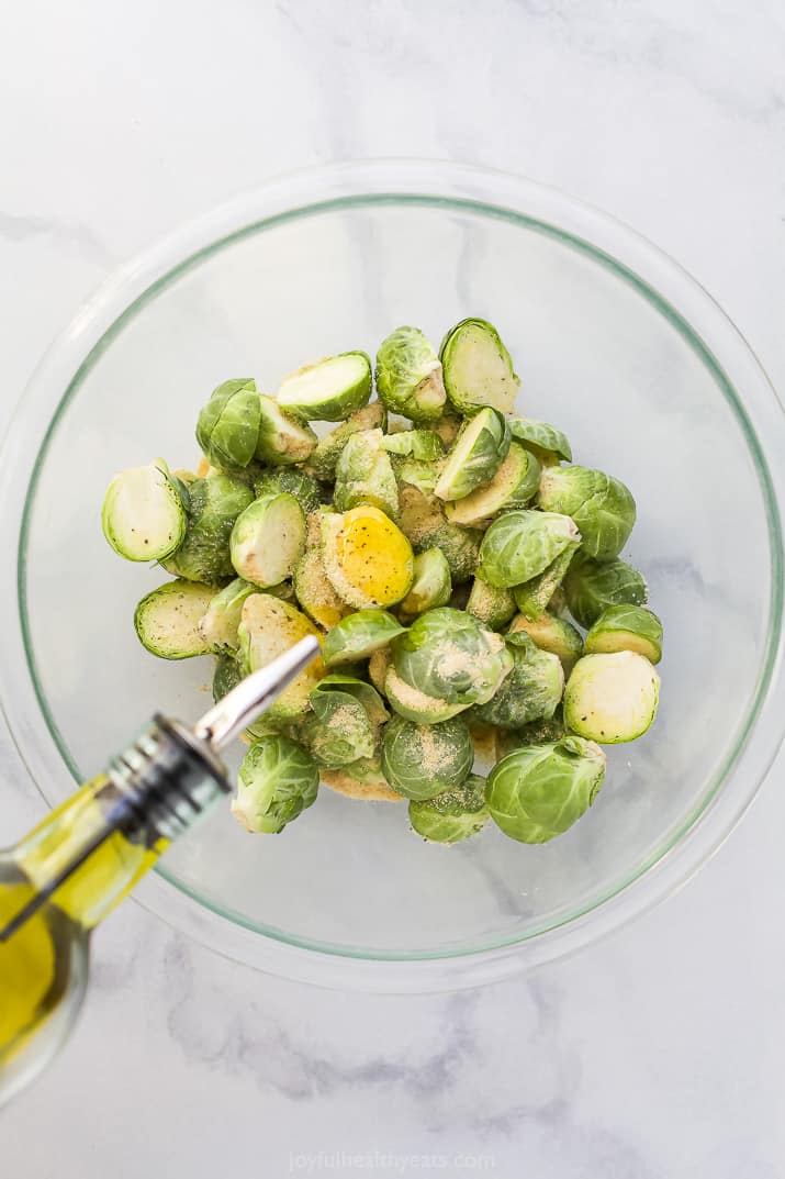 a bowl of brussel sprouts being seasoned