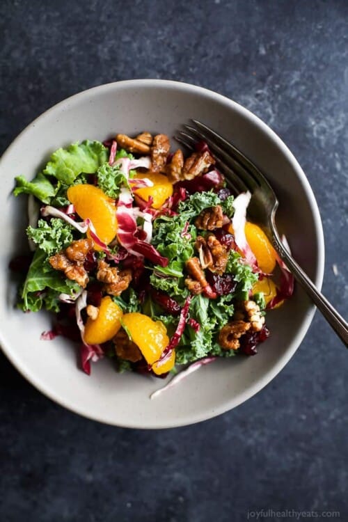 kale salad with cranberry and orange in a bowl