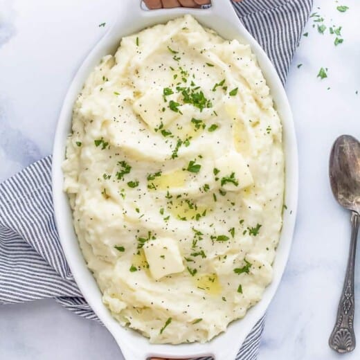 hands holding a baking dish with creamy mashed potatoes