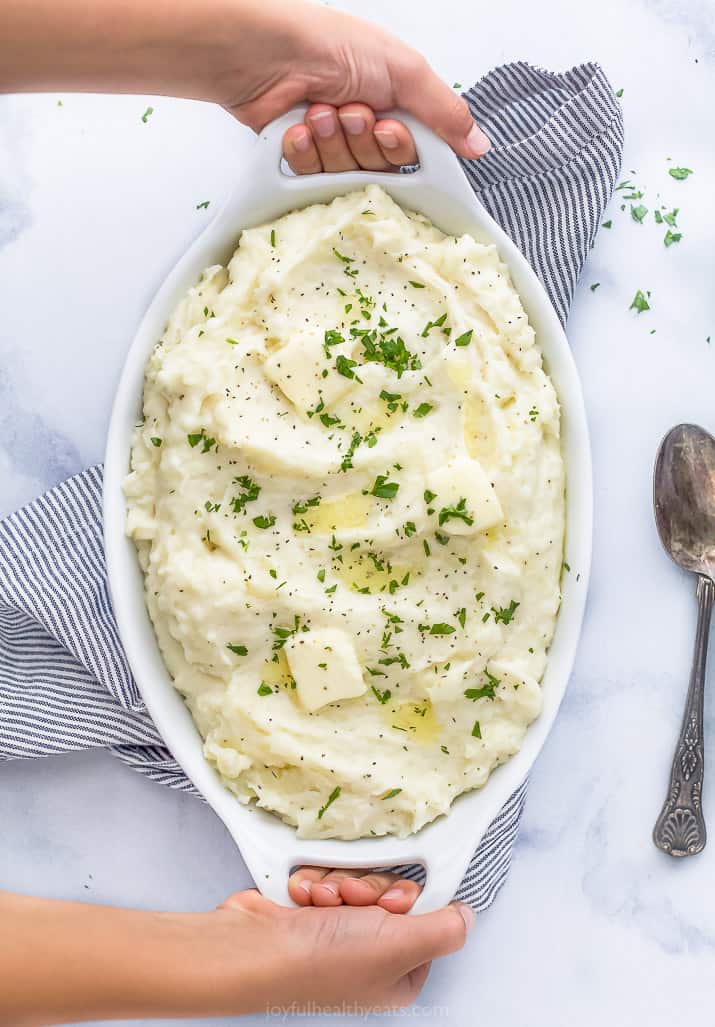 hands holding a baking dish with creamy mashed potatoes