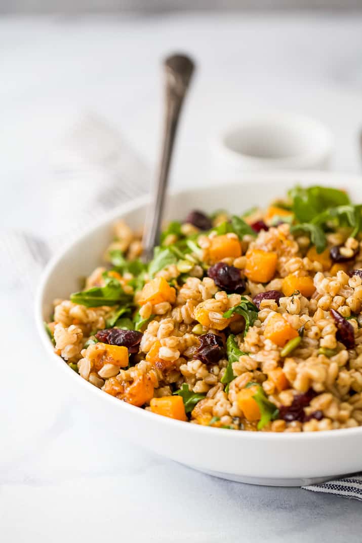 side photo of a bowl filled with fall farro salad and a spoon