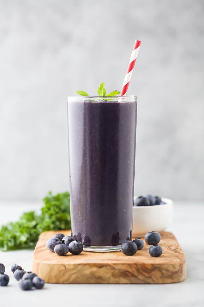 A Kale Protein Smoothie in a Tall Glass with a Red and White Striped Straw