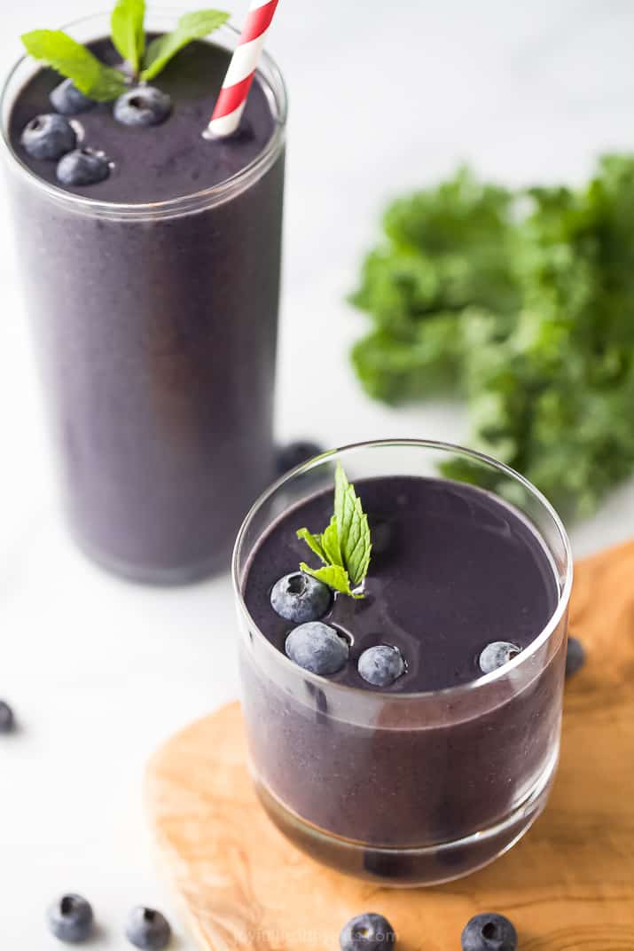 two glasses with dark purple smoothie and bluberries and mint as a garnish