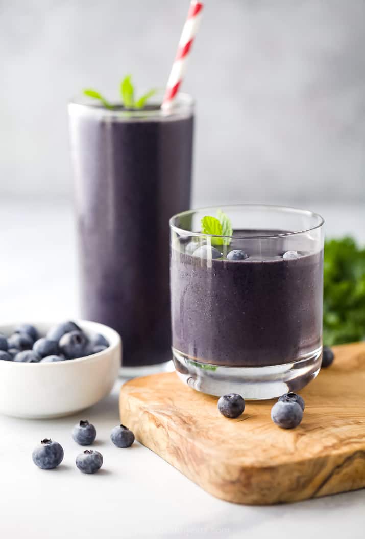 Two Glasses of Kale Smoothies Next to a Bowl of Fresh Blueberries