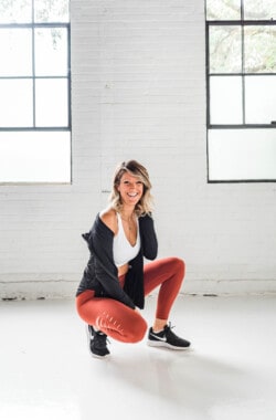 girl in workout clothes squatting and smiling