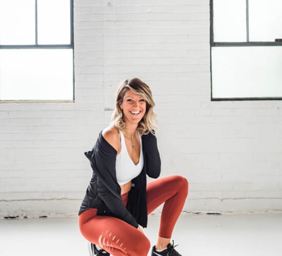 girl in workout clothes squatting and smiling