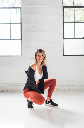 girl in workout clothes squatting and smiling