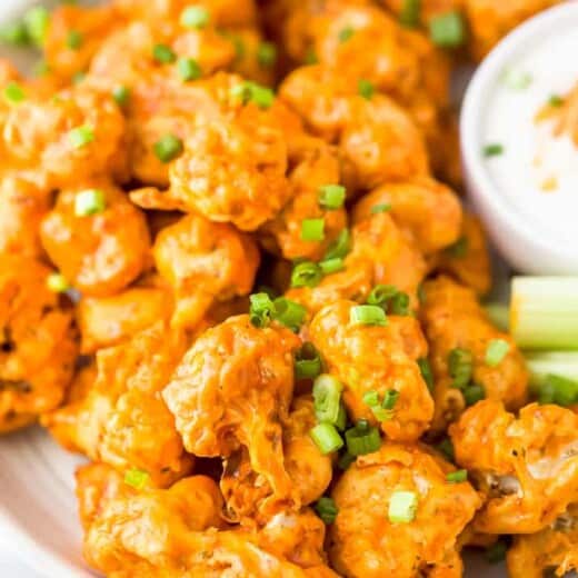 A Plate of Buffalo Cauliflower Bites Topped with Green Onions