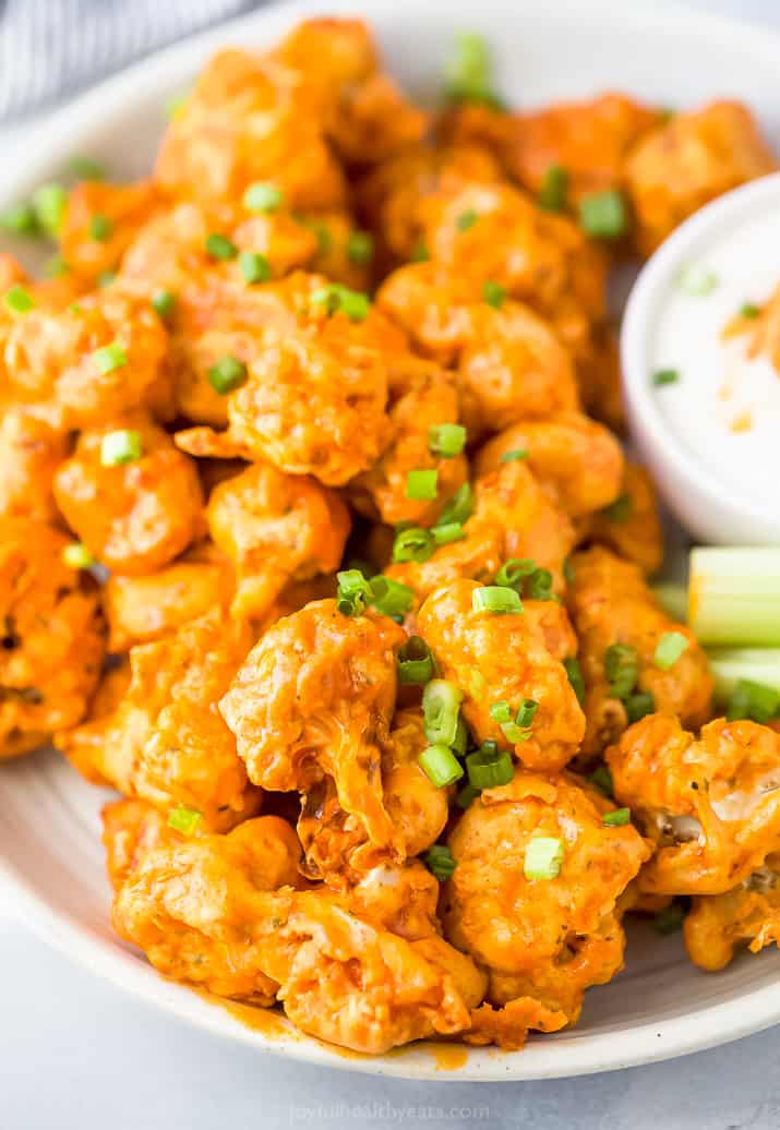 A Plate of Buffalo Cauliflower Bites Topped with Green Onions