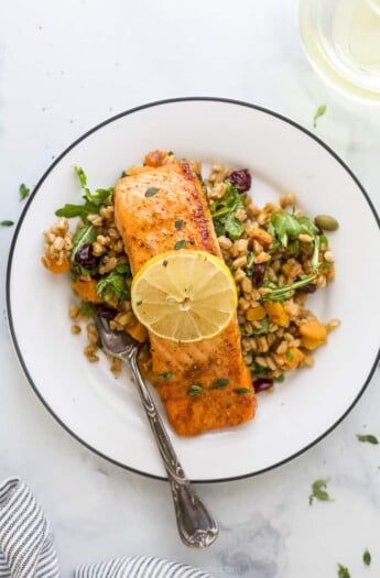 A Salmon Filet on a Plate with a Fork and a Slice of Lemon on Top