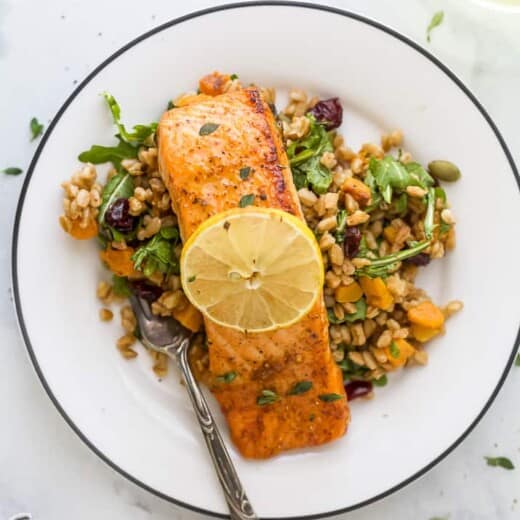 A Salmon Filet on a Plate with a Fork and a Slice of Lemon on Top