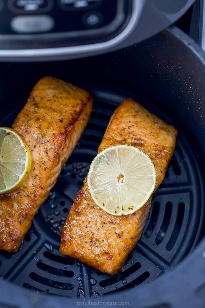 Two Salmon Filets in an Air Fryer with Lemon Slices on Top