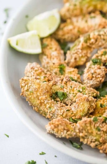 crispy avocado fries on a plate with lime wedges