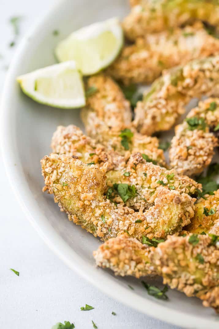 crispy avocado fries on a plate with lime wedges