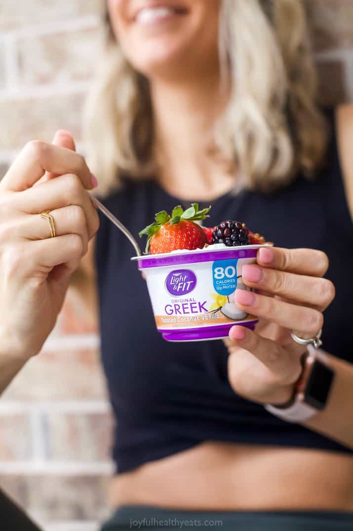 girl in workout clothes holding light and fit yogurt