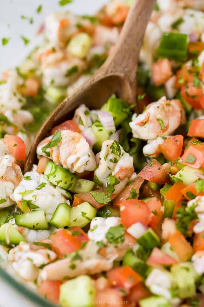 A Wooden Spoon Mixing Around Shrimp Ceviche in a Bowl