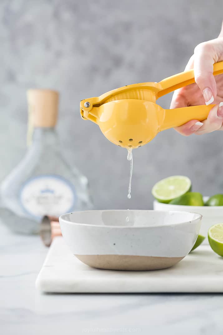 A Mustard Yellow Lime Squeezer Squeezing the Juice of a Lime into a Bowl