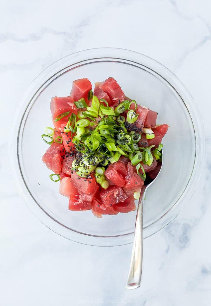 Pieces of Tuna in a Bowl with the Marinade Ingredients and a Spoon