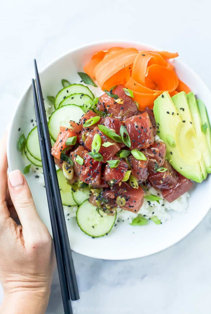 A Hawaiian Poke Bowl on a Countertop with a Hand on the Edge of the Bowl