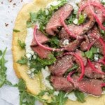 flatbread pizza topped with steak and arugula