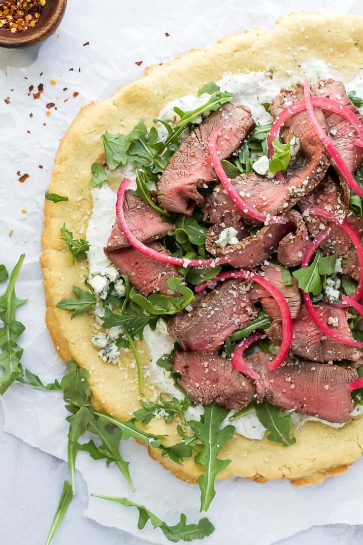 flatbread pizza topped with steak and arugula