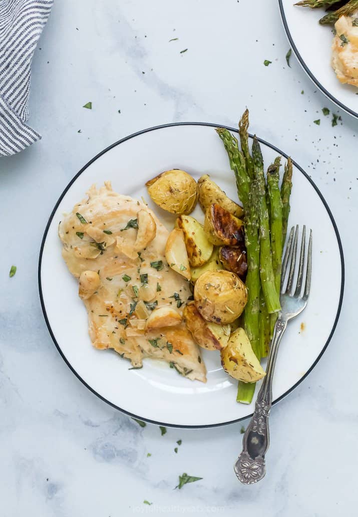 chicken with creamy garlic sauce on a plate with potatoes and asparagus