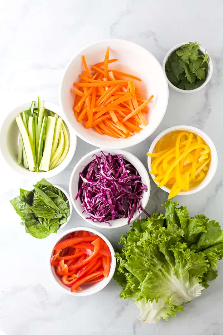 Bowls of Julienned Veggies Next to a Pile of Cabbage on a Countertop