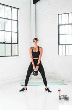 girl holding a kettle bell doing sumo squats
