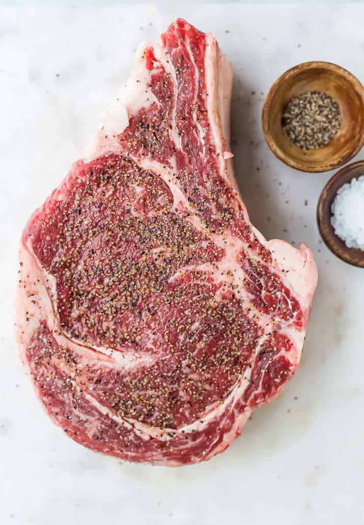 seasoned raw ribeye with a bone