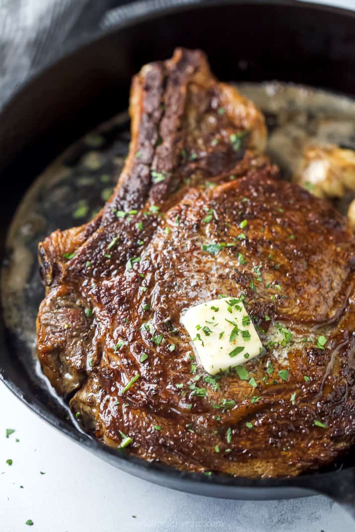 close up of a cowboy steak in skillet with butter on top