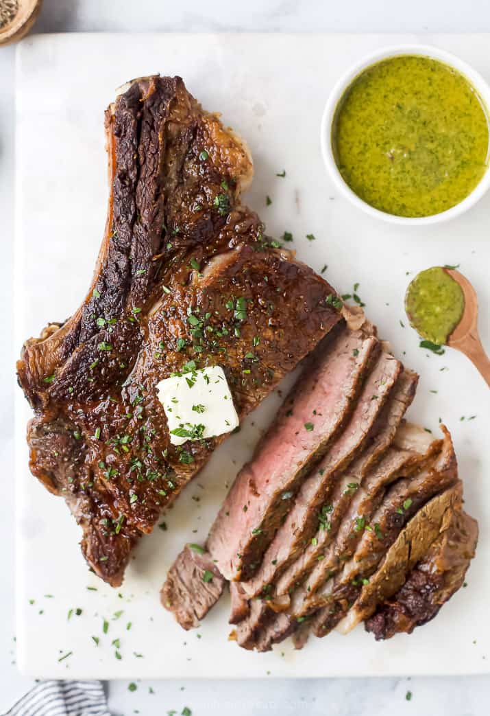 sliced bone in ribeye with chimichurri sauce on the side