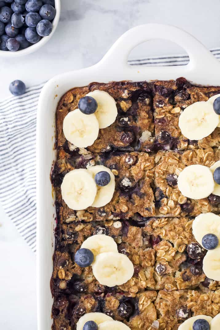 A closeup of a pan of baked oatmeal topped with banana slices and blueberries