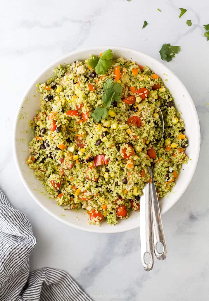 A big white bowl of fiesta quinoa salad, topped with parsley, and two silver forks.