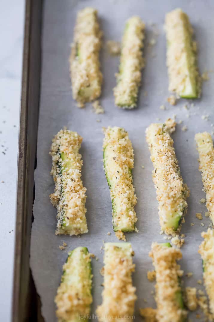 Breaded zucchini fries on parchment paper ready to be cooked