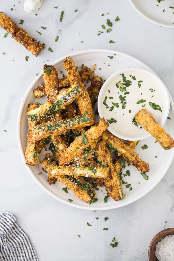 A plate of zucchini fries with a white dipping sauce