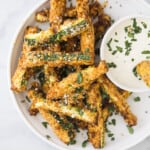 Close up of crispy zucchini fries on a white plate