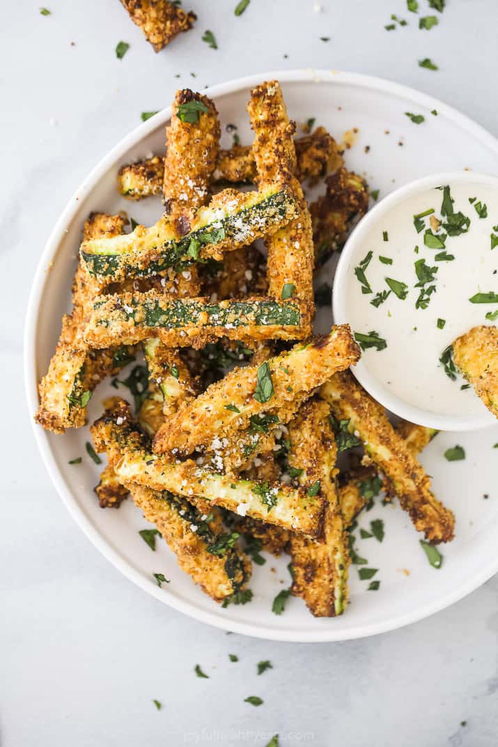 Close up of crispy zucchini fries on a white plate
