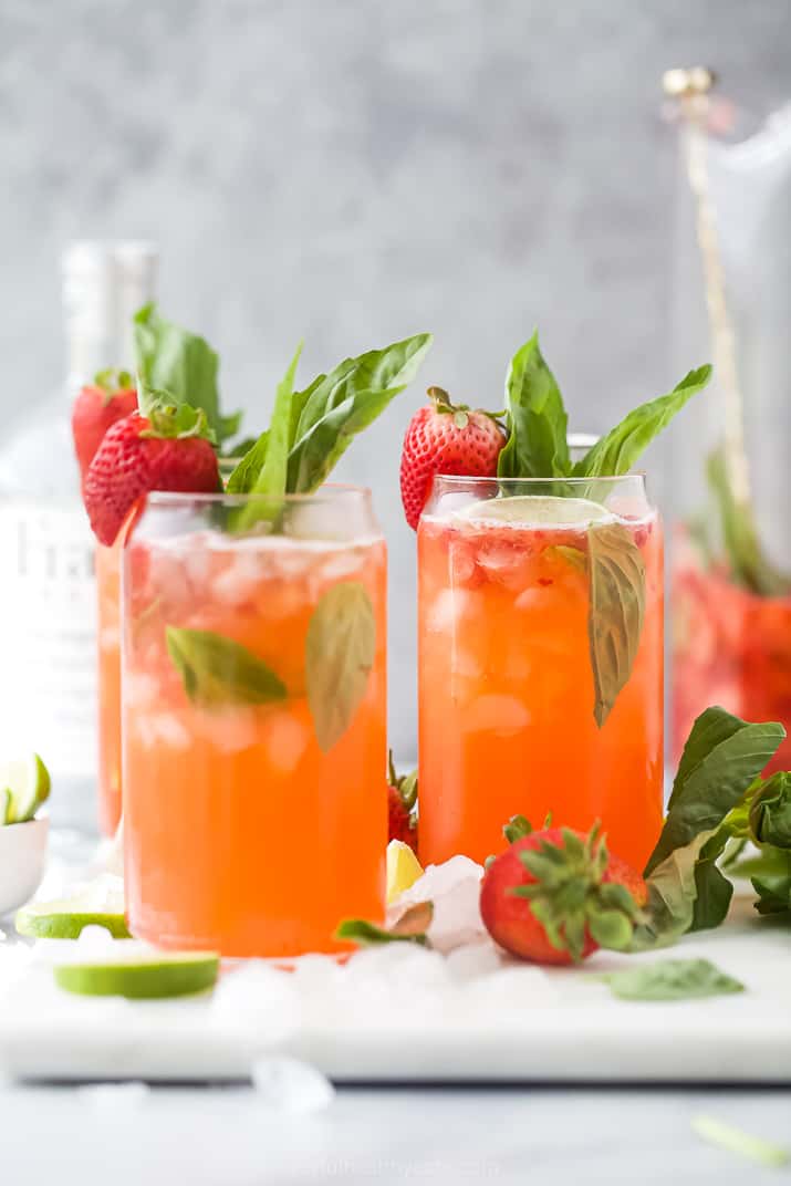 Two glasses of a strawberry vodka cocktail garnished with basil
