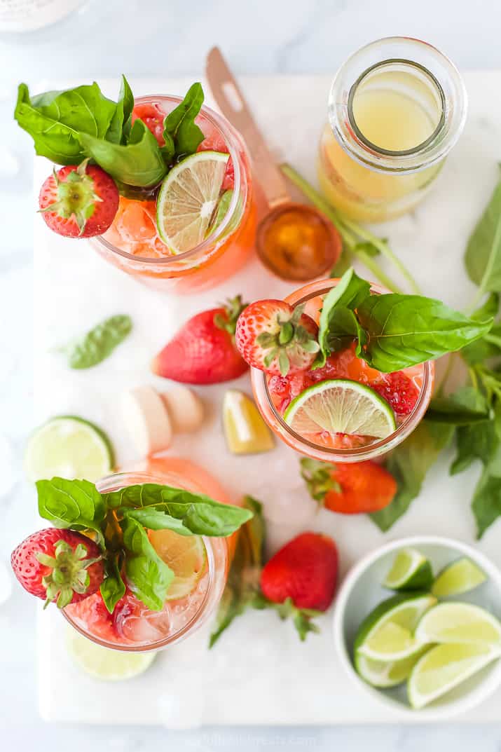 Aerial view of three strawberry vodka cocktails with strawberry, lime and basil