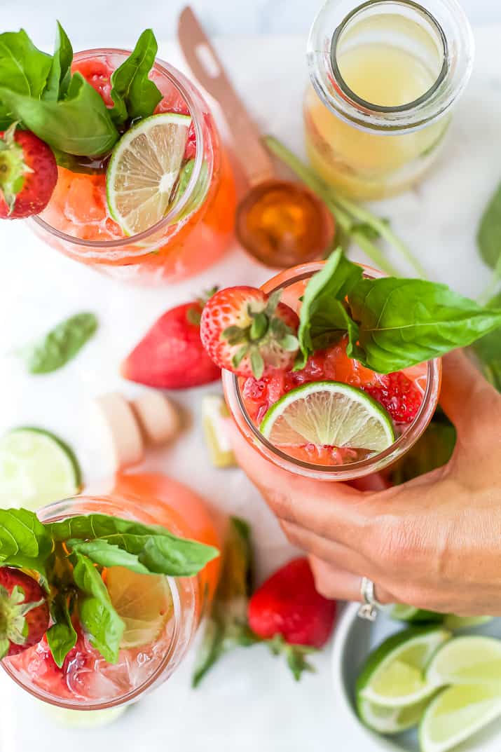 A hand holding a strawberry vodka cocktail 