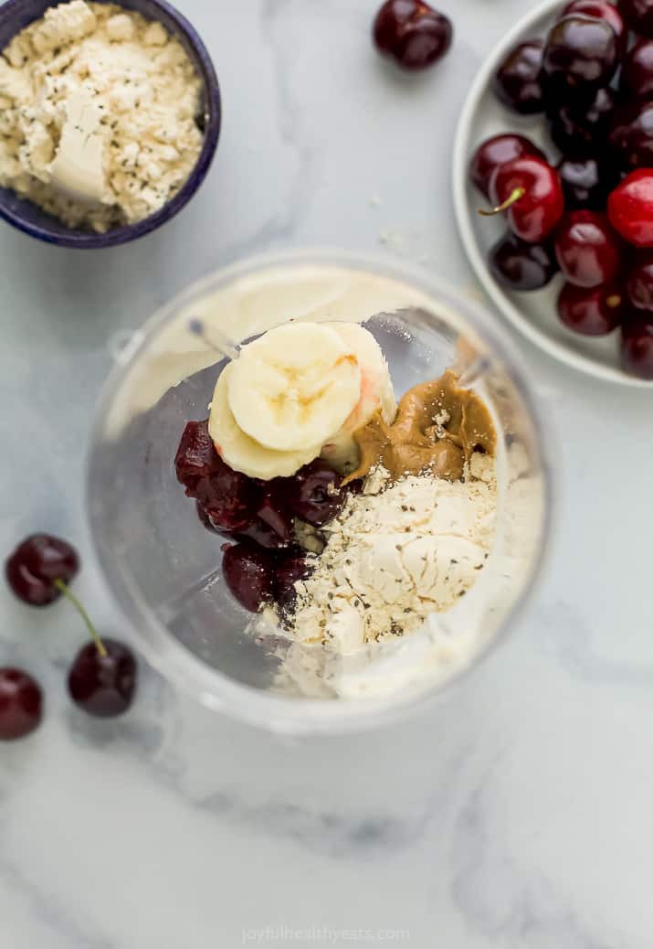 An easy smoothie bowl recipe with cherries, bananas, creamy almond butter, and protein powder. Add toppings for a high protein breakfast! Cherry smoothie ingredients combined in a blender.